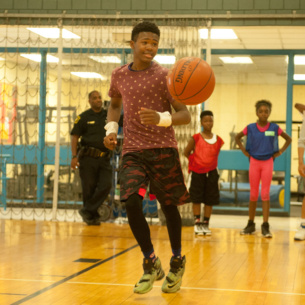 photo of teen boy playing basketball in a gym