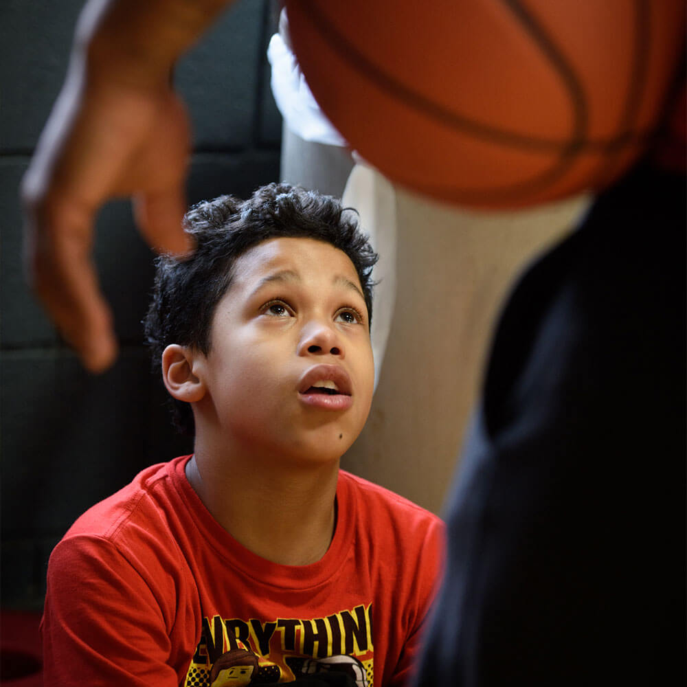photo of young boy looking up at basketball mentor